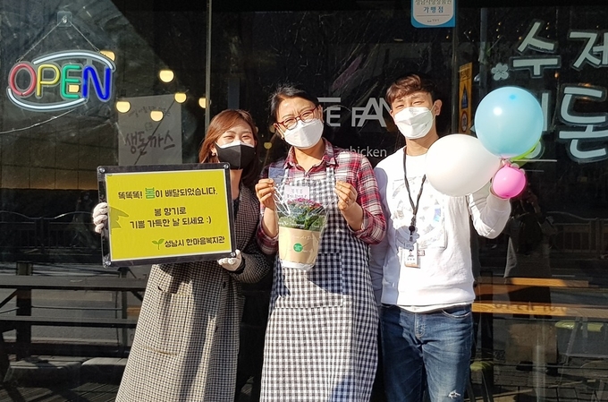 <p>성남시 한마음복지관 직원이 상점과 약국에 화분을 전달하고 있다</p>