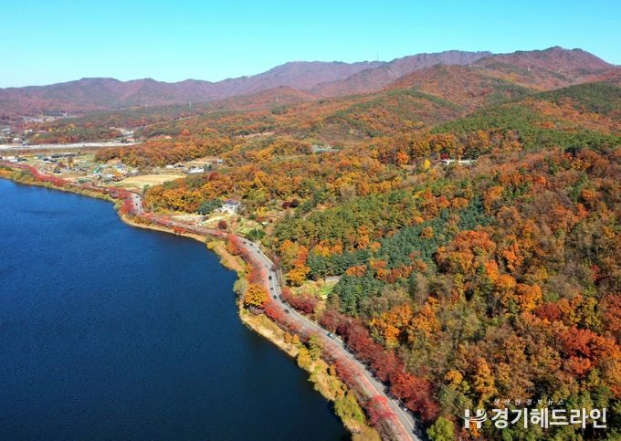 광교저수지 수변 산책로와 광교산 자락이 가을철 오색 단풍으로 뒤덮인 모습.