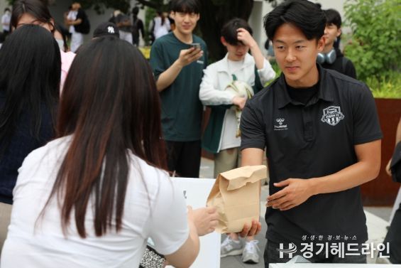 8일 아주대 학생회관 앞에서 열린 찾아가는 사랑의 밥차 ‘청년들 힘내세요’ 무료 급식 행사에 참여한 수원FC 이승우 선수가 한 대학생에게 햄버거와 음료수를 건네고 있다.