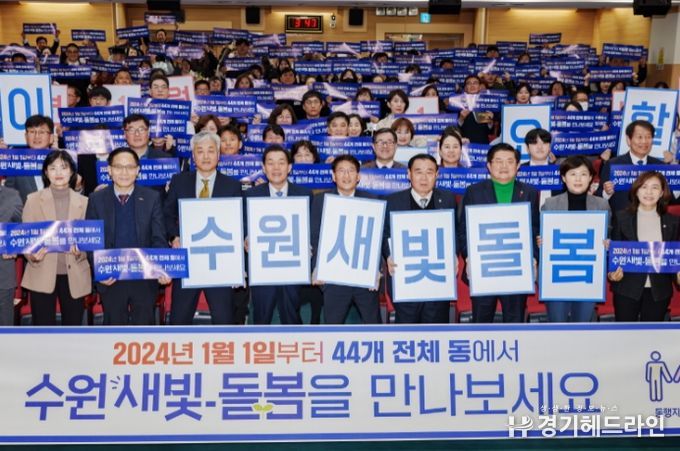 지난해 12월 수원특례시 관계자들이 수원새빛돌봄 전체 동 확대를 홍보하는 손팻말을 들어 보이고 있다.